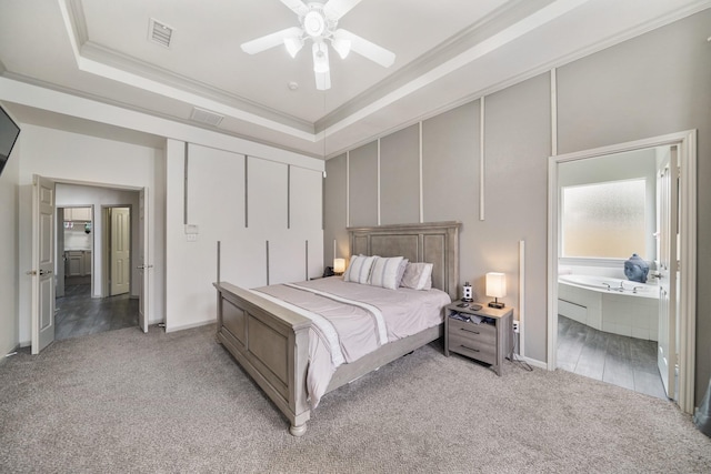 bedroom featuring connected bathroom, ornamental molding, light colored carpet, ceiling fan, and a raised ceiling