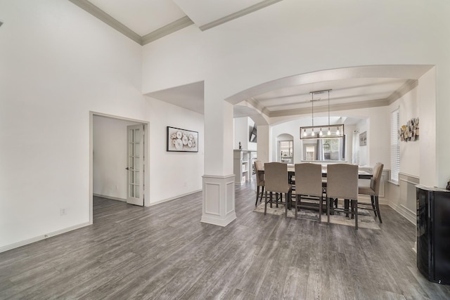 dining area with ornamental molding, a notable chandelier, and dark hardwood / wood-style flooring