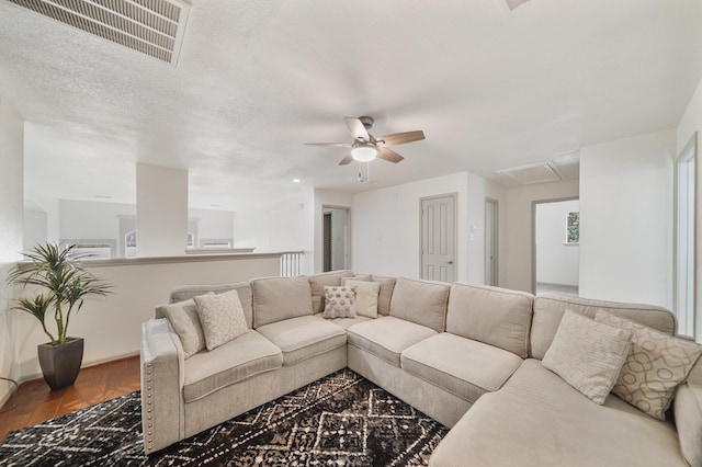 living room with hardwood / wood-style flooring, ceiling fan, and a textured ceiling