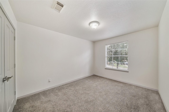 carpeted spare room featuring a textured ceiling