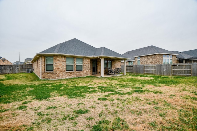 rear view of property with a yard, a patio, and central air condition unit