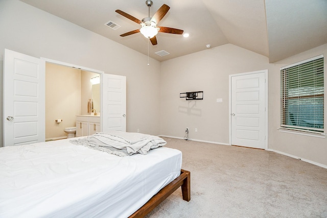 bedroom with ceiling fan, ensuite bathroom, carpet flooring, and vaulted ceiling