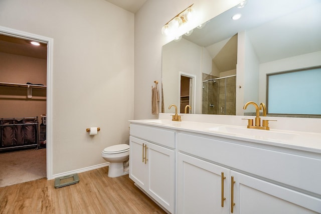 bathroom featuring vaulted ceiling, a shower with shower door, hardwood / wood-style flooring, vanity, and toilet