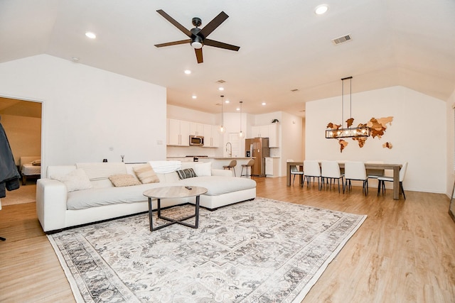 living room with lofted ceiling, sink, light hardwood / wood-style floors, and ceiling fan