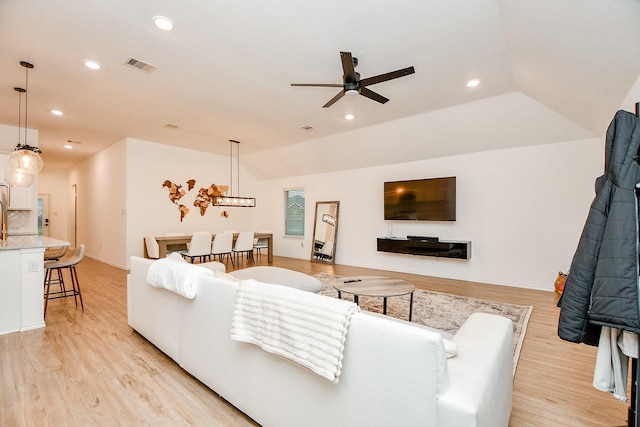 living room featuring vaulted ceiling, ceiling fan, and light hardwood / wood-style flooring