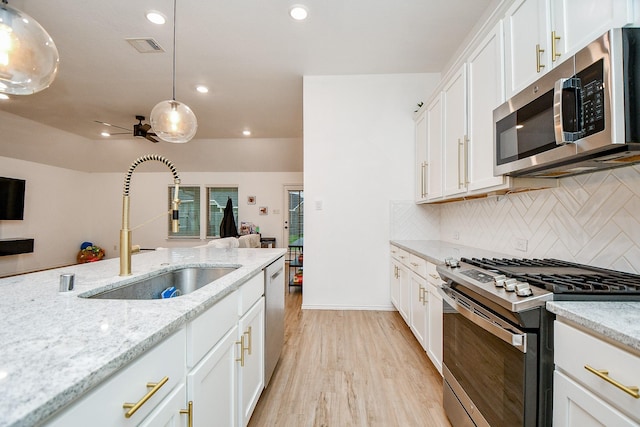 kitchen featuring sink, hanging light fixtures, appliances with stainless steel finishes, light stone countertops, and white cabinets