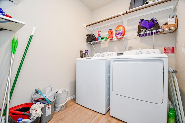 clothes washing area featuring washing machine and clothes dryer and light wood-type flooring