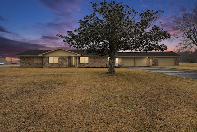 ranch-style house with a garage and a yard