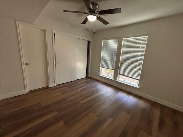 unfurnished bedroom with dark wood-type flooring, ceiling fan, and a closet