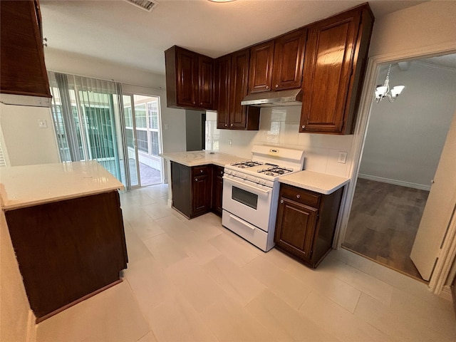 kitchen featuring pendant lighting, gas range gas stove, dark brown cabinets, tasteful backsplash, and kitchen peninsula