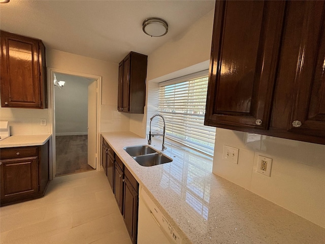 kitchen featuring sink, dark brown cabinets, light stone countertops, and dishwasher