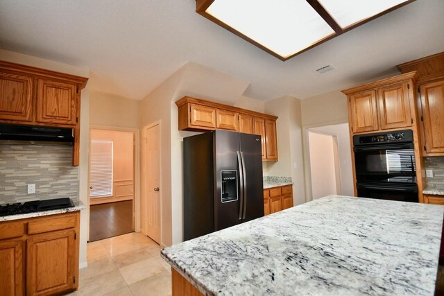 kitchen with backsplash, light tile patterned floors, and black appliances