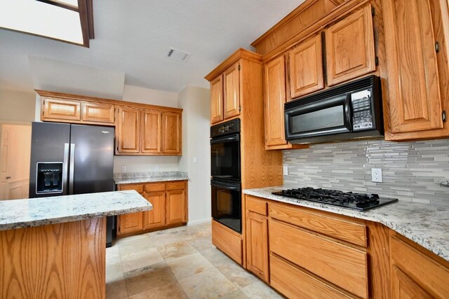 kitchen featuring backsplash, black appliances, and light stone countertops