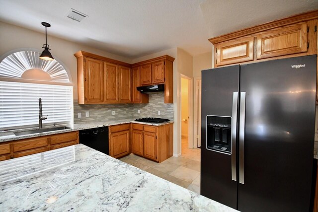 kitchen featuring sink, light stone counters, pendant lighting, decorative backsplash, and black appliances