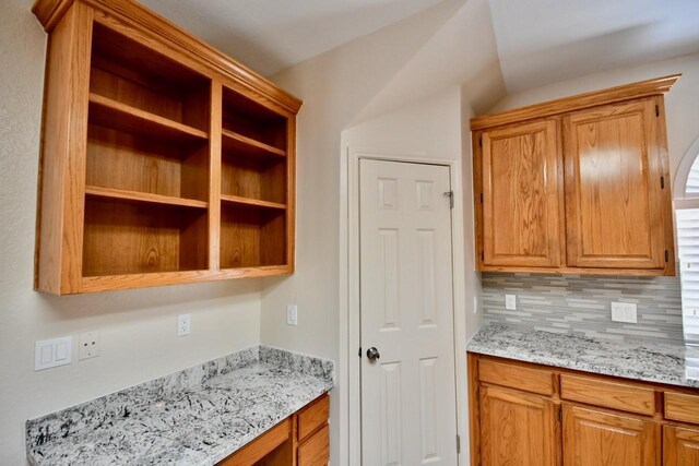 kitchen featuring tasteful backsplash, light stone countertops, and built in desk