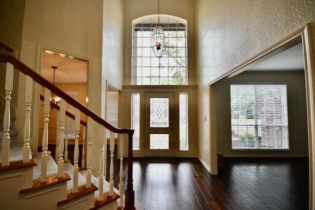 entrance foyer featuring an inviting chandelier, dark hardwood / wood-style floors, and a high ceiling