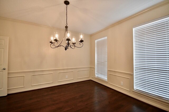 empty room with crown molding, dark wood-type flooring, and a notable chandelier