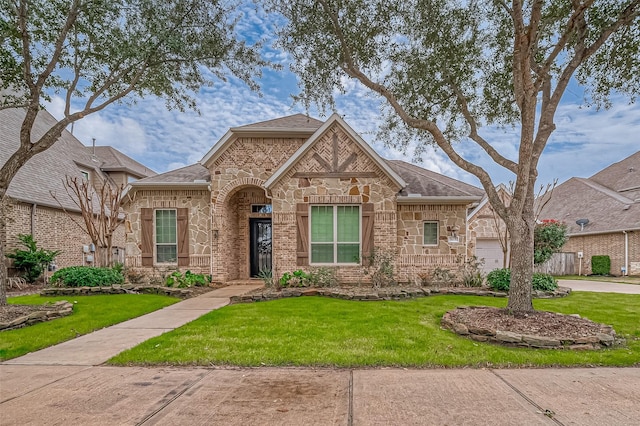 view of front of property with a garage, stone siding, roof with shingles, and a front yard