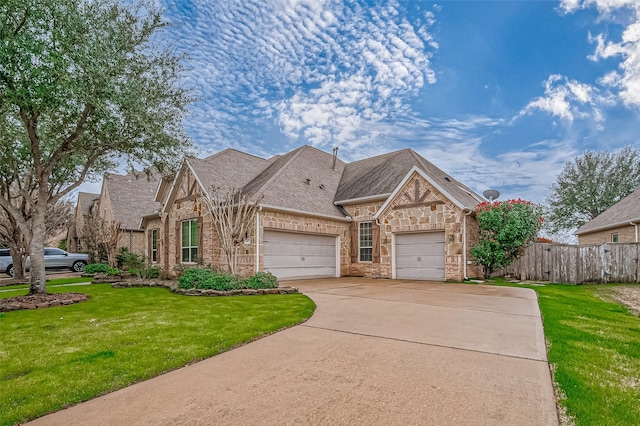 french country inspired facade featuring a garage, driveway, a front yard, and fence