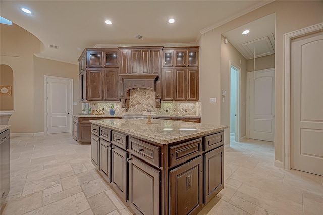 kitchen featuring glass insert cabinets, light stone countertops, a kitchen island, decorative backsplash, and stone tile flooring