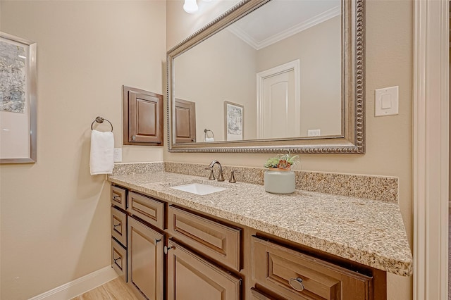 bathroom featuring baseboards, wood finished floors, crown molding, and vanity