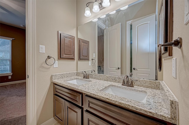 bathroom with double vanity, a sink, and baseboards