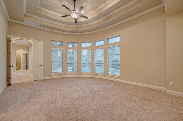 unfurnished room featuring arched walkways, a tray ceiling, light carpet, and visible vents