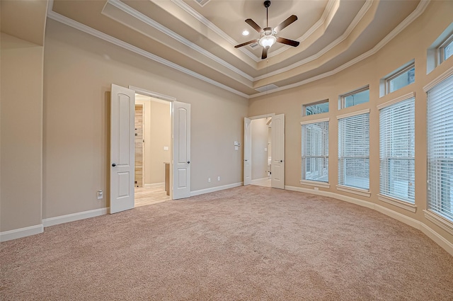 empty room with carpet, a raised ceiling, ornamental molding, a ceiling fan, and baseboards