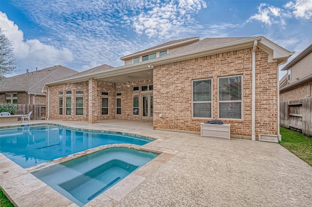 view of swimming pool featuring a patio area, fence, and a pool with connected hot tub