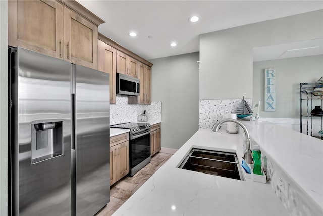 kitchen with appliances with stainless steel finishes, light stone countertops, sink, and decorative backsplash