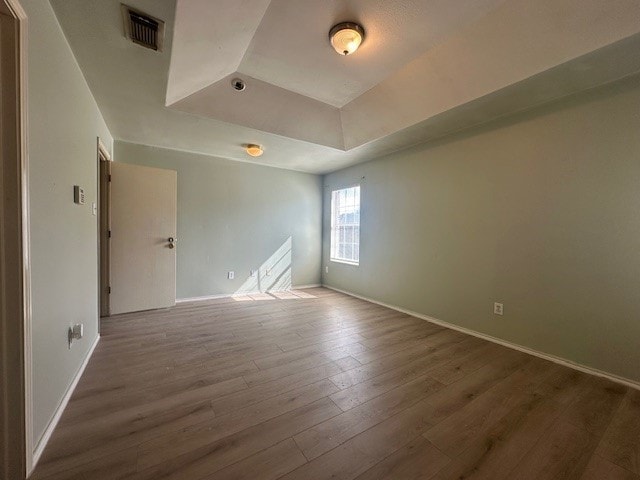 empty room featuring hardwood / wood-style flooring and a raised ceiling