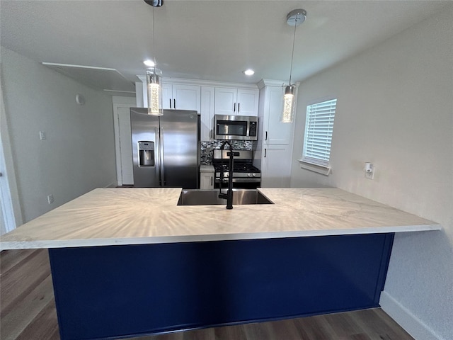 kitchen featuring appliances with stainless steel finishes, white cabinetry, hanging light fixtures, dark hardwood / wood-style floors, and kitchen peninsula