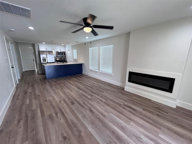 unfurnished living room with ceiling fan and hardwood / wood-style floors