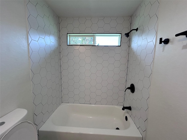 bathroom featuring tiled shower / bath combo and toilet