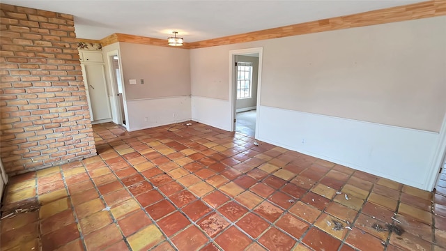 unfurnished room with tile patterned floors and brick wall