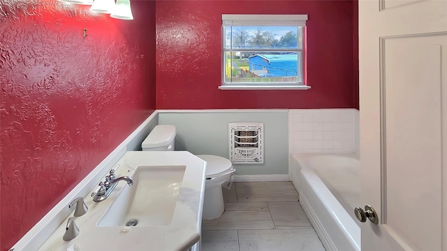 bathroom featuring heating unit, sink, toilet, and a bathing tub