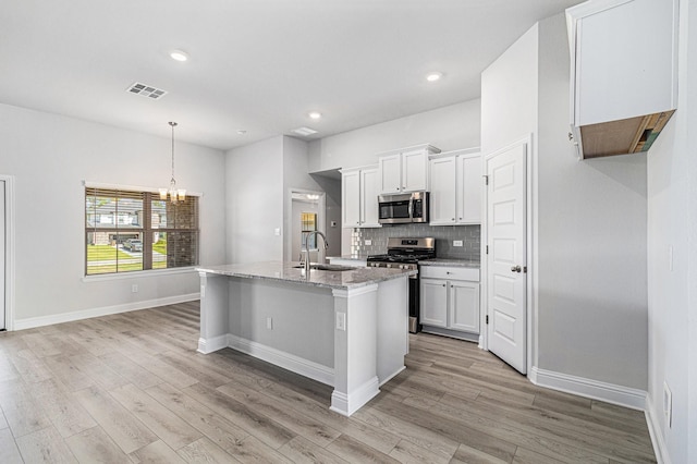 kitchen featuring sink, stainless steel appliances, white cabinets, and light stone countertops