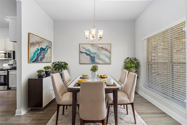 dining area with wood-type flooring and an inviting chandelier