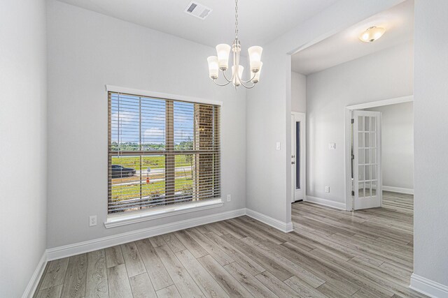 empty room with light hardwood / wood-style flooring and a notable chandelier