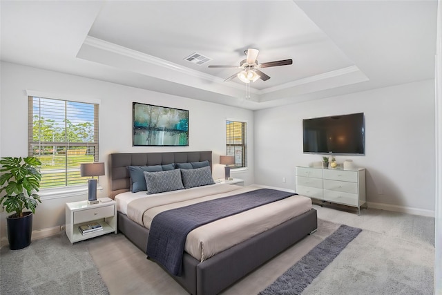 carpeted bedroom featuring a tray ceiling, ornamental molding, and ceiling fan