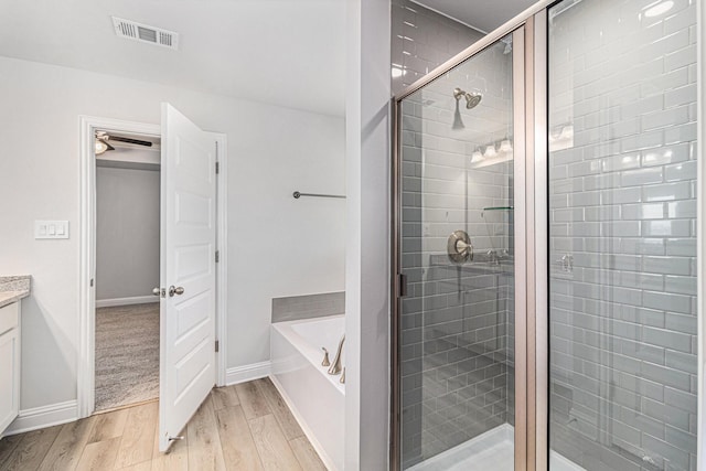 bathroom with wood-type flooring, vanity, and plus walk in shower