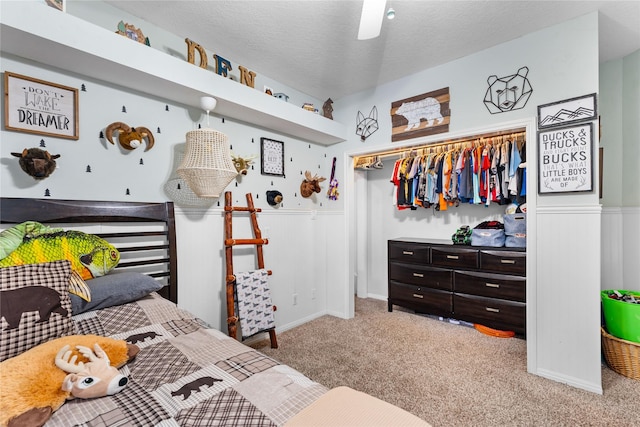 bedroom with ceiling fan, carpet floors, and a textured ceiling