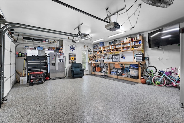 garage with a garage door opener, stainless steel fridge, and a workshop area