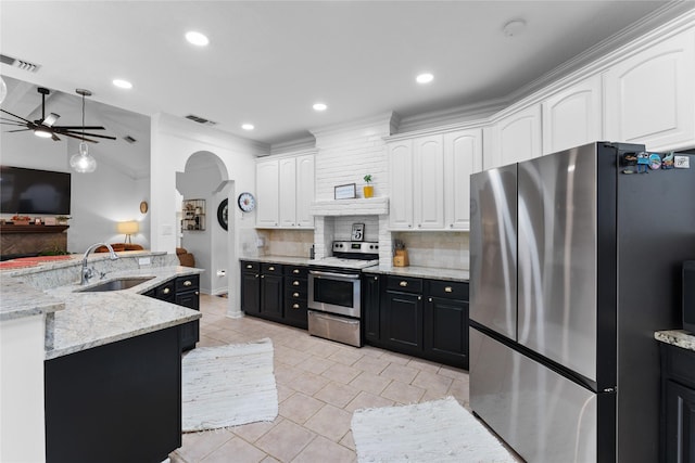 kitchen featuring sink, appliances with stainless steel finishes, white cabinetry, light stone counters, and decorative backsplash