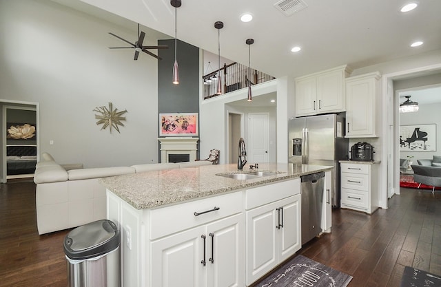 kitchen featuring sink, white cabinetry, decorative light fixtures, a center island with sink, and dishwasher