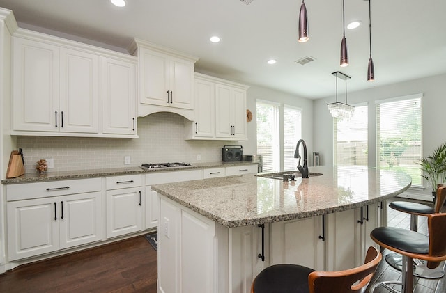 kitchen with pendant lighting, sink, a center island with sink, and white cabinets