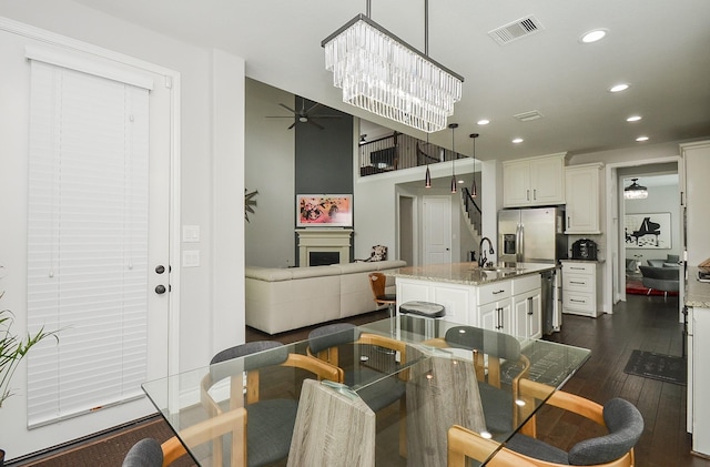 dining space with sink, ceiling fan with notable chandelier, and dark hardwood / wood-style flooring