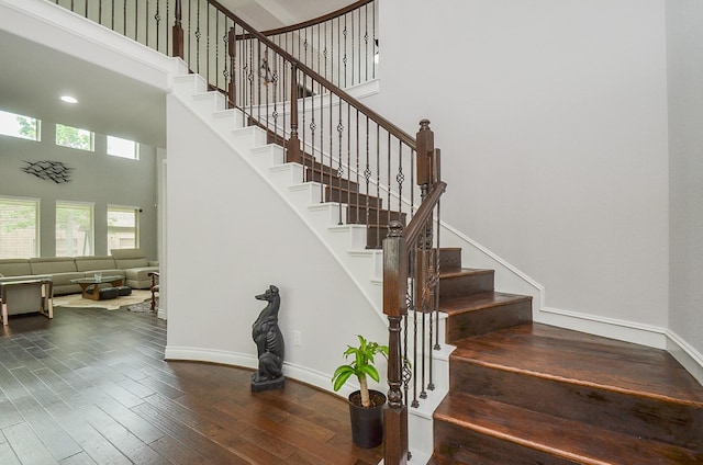 stairway featuring a towering ceiling and wood-type flooring