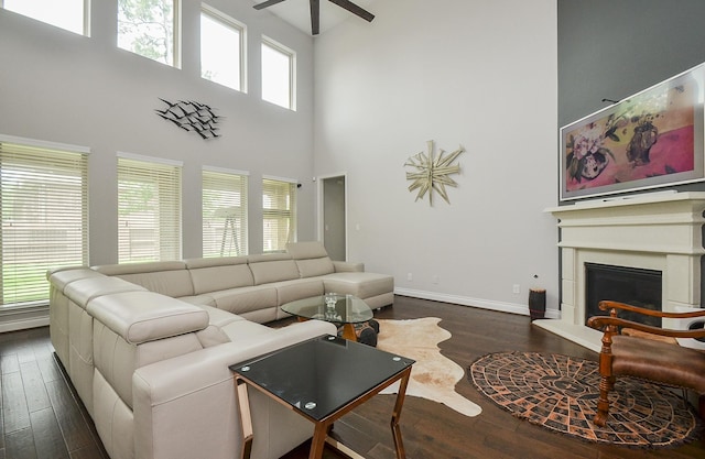 living room with a towering ceiling, dark hardwood / wood-style floors, and ceiling fan