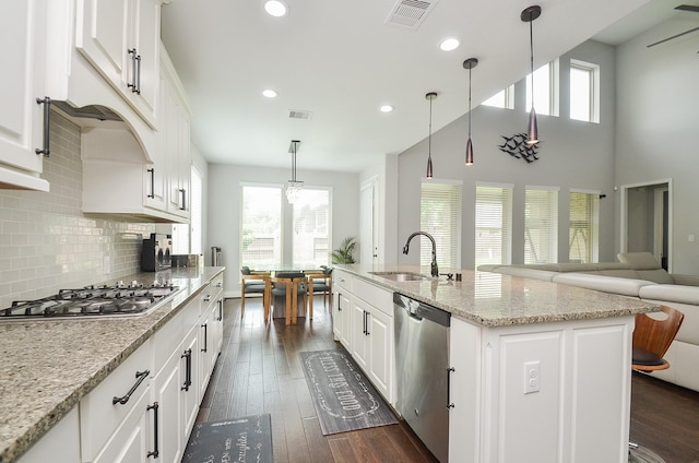 kitchen with sink, hanging light fixtures, stainless steel appliances, a kitchen island with sink, and white cabinets